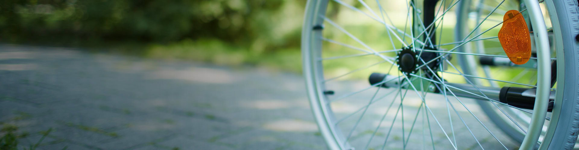 Close up of a wheelchair moving along a sidewalk.